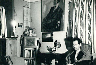 Saenz seated below portrait of him by Enrique Arnal